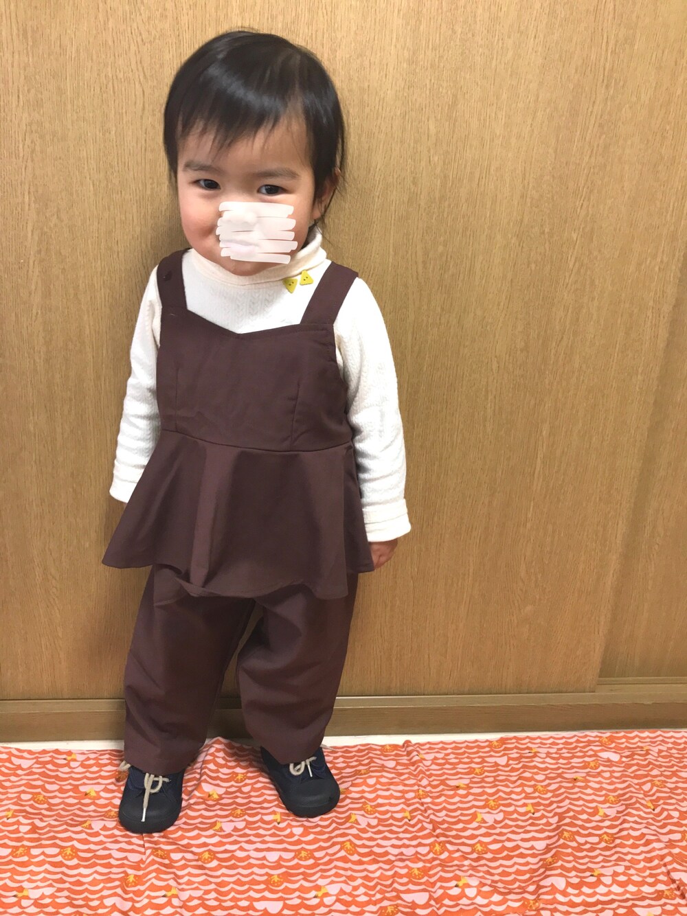 ブラウン系のチュニック、ホワイト系のTシャツ/カットソーを着用したキッズの冬コーディネートの1枚目の写真