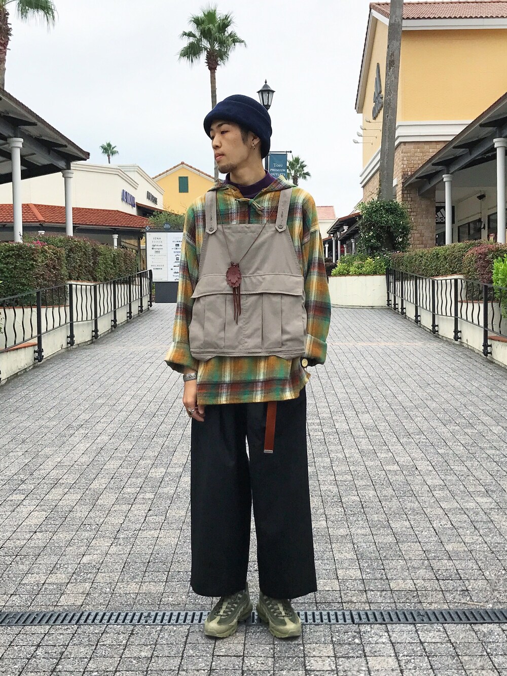 ベージュ系のベスト、イエロー系のパーカー、ブラック系のスラックスを着用したメンズの秋コーディネートの1枚目の写真