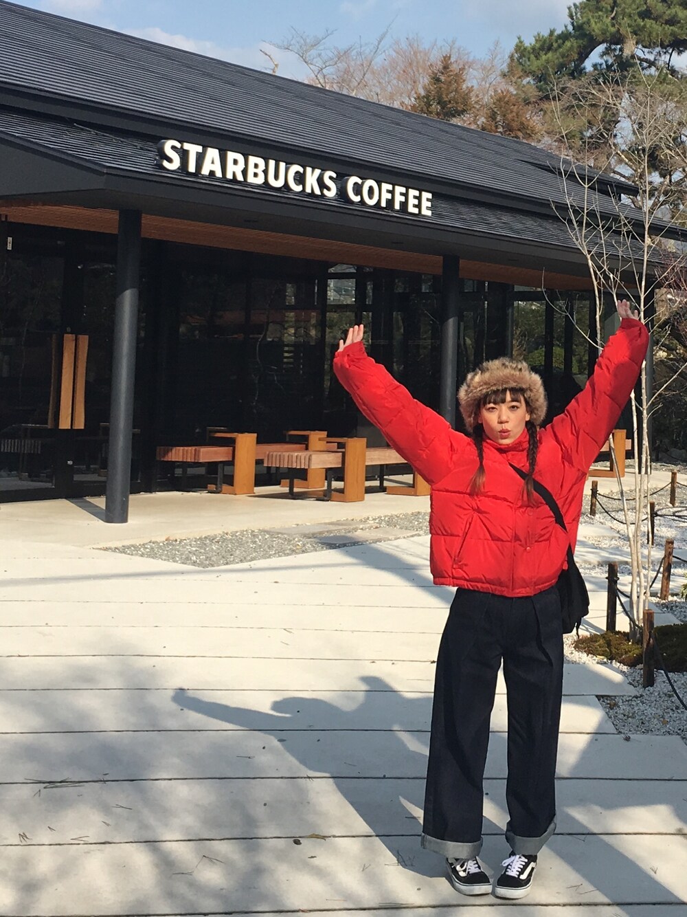 レッド系のダウンジャケット/コート、ブルー系のデニムパンツ、ブラック系のスニーカーを着用したレディースの冬コーディネートの1枚目の写真