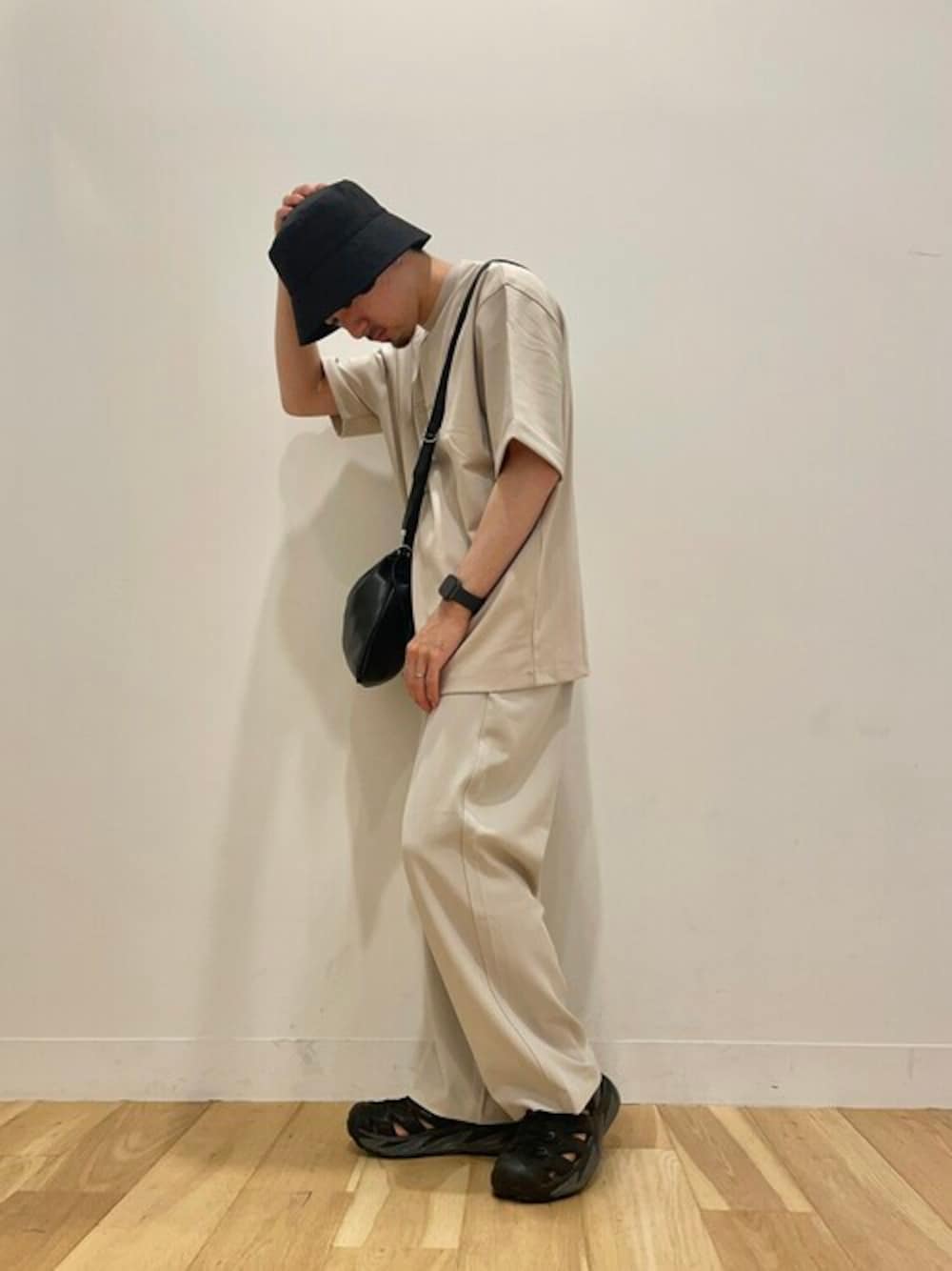 ベージュ系のTシャツ/カットソー、ベージュ系のスラックス、ブラック系のバックパック/リュックを着用したメンズの夏コーディネートの1枚目の写真