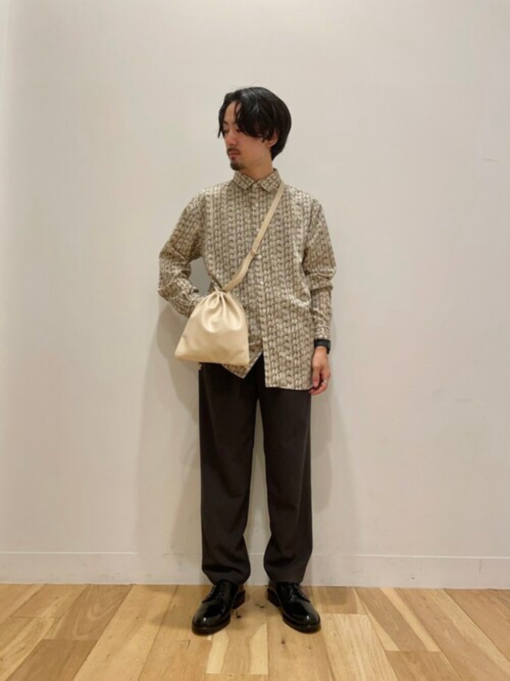 ベージュ系のシャツ/ブラウス、グレー系のスラックス、ベージュ系のショルダーバッグを着用したメンズの夏コーディネートの1枚目の写真