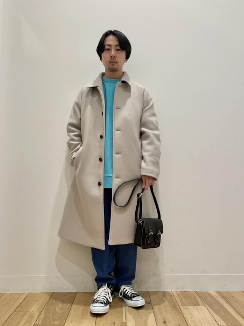 ベージュ系のステンカラーコート、ブルー系のスウェット、ブルー系のスラックスを着用したメンズの冬コーディネートの1枚目の写真