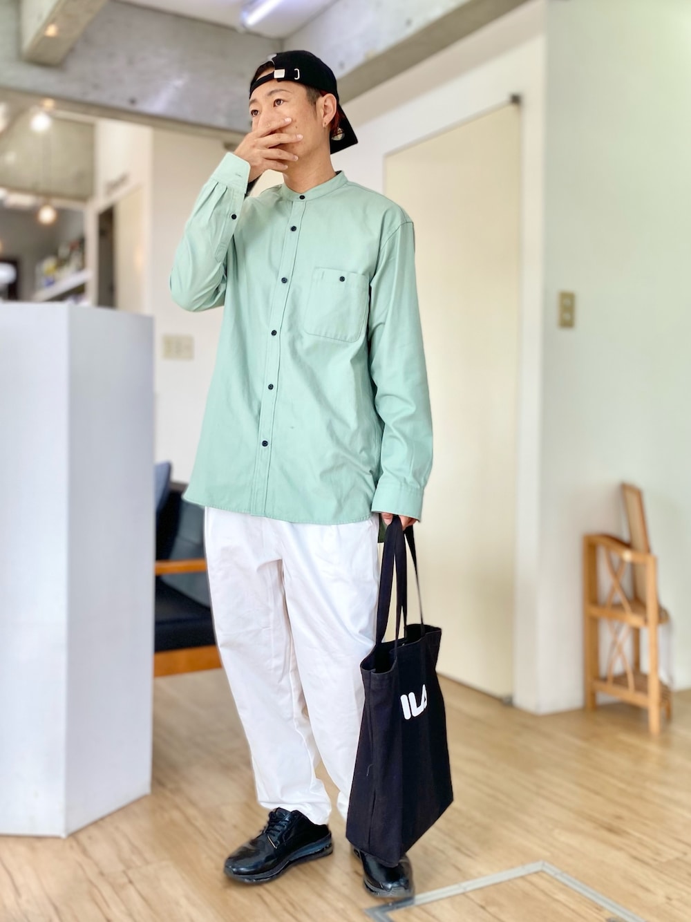 ホワイト系のチノパンツ、グリーン系のシャツ/ブラウス、ブラック系のトートバッグを着用したメンズの春コーディネートの1枚目の写真