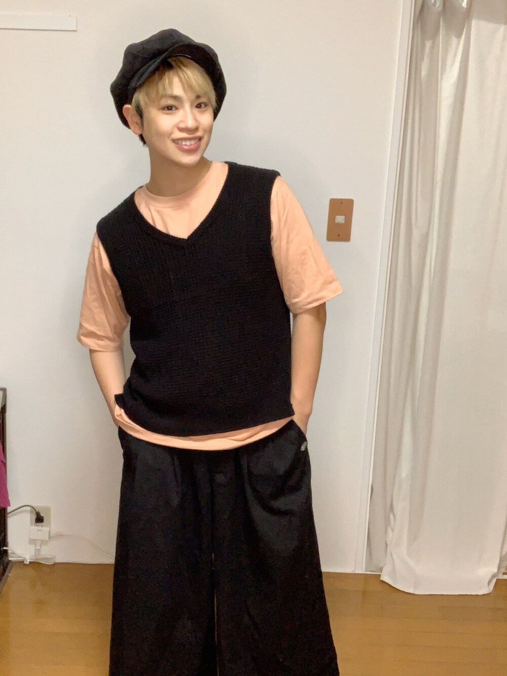 ブラック系のニット/セーター、ピンク系のTシャツ/カットソー、ブラック系のチノパンツを着用したメンズの春コーディネートの1枚目の写真