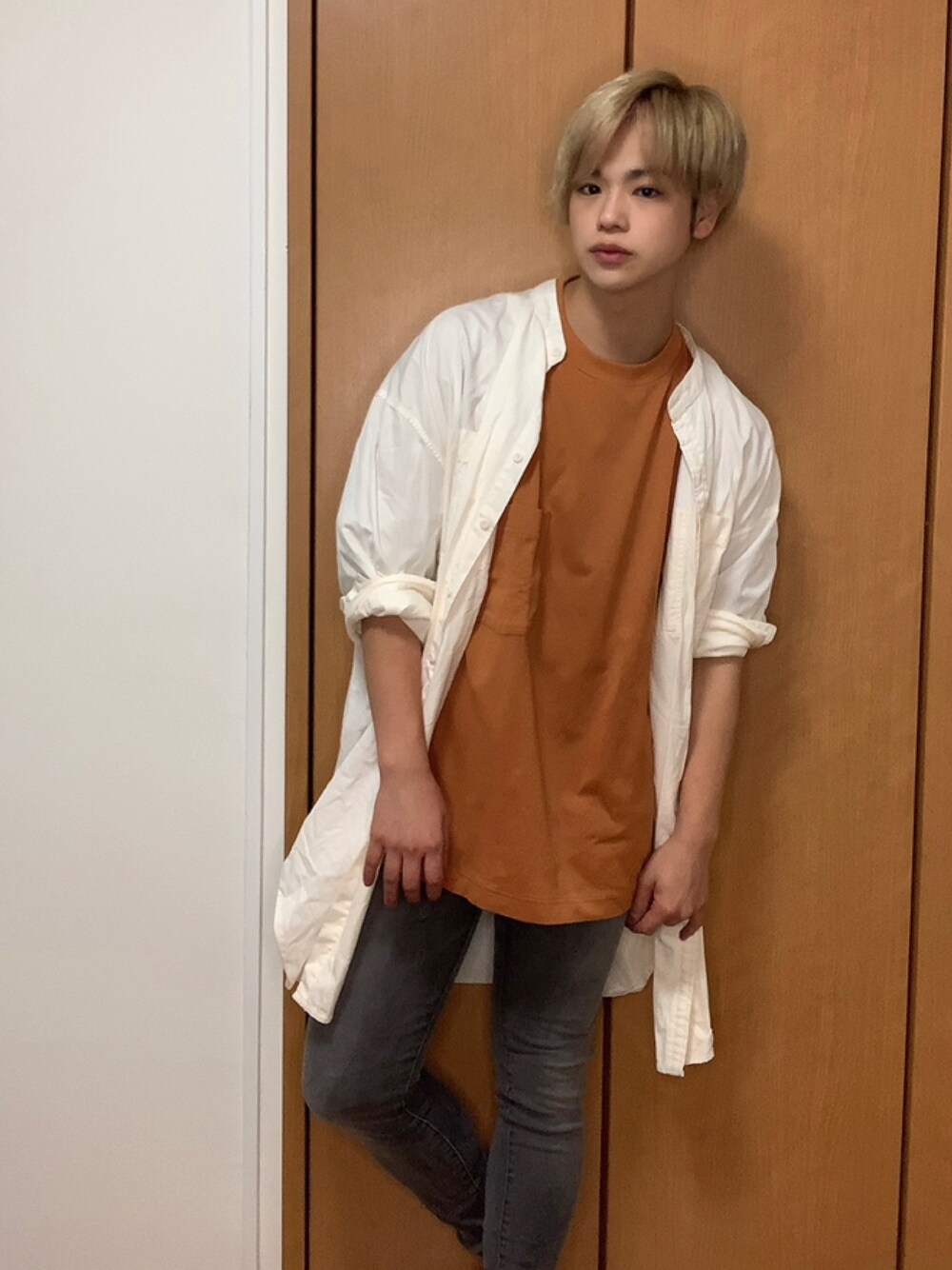 オレンジ系のTシャツ/カットソー、グレー系のデニムパンツを着用したメンズの秋コーディネートの1枚目の写真