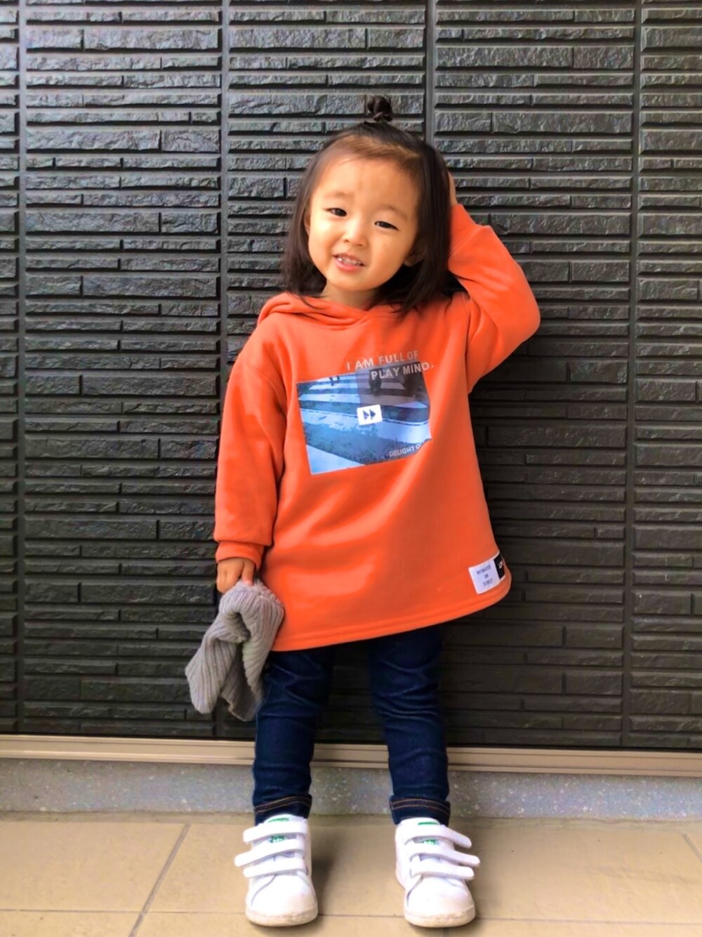 オレンジ系のパーカー、ブルー系のデニムパンツ、ホワイト系のスニーカーを着用したキッズの冬コーディネートの1枚目の写真