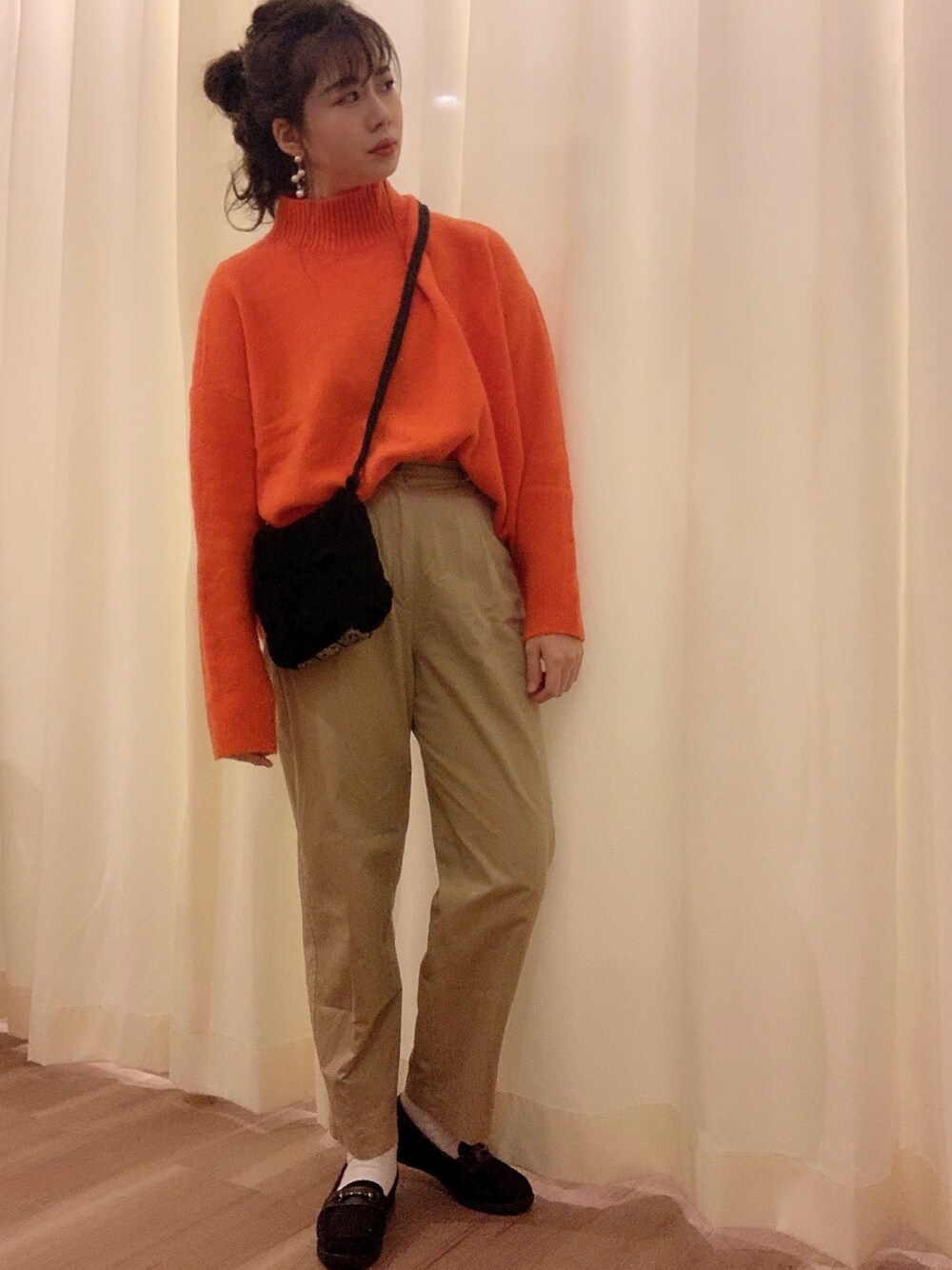 ベージュ系のチノパンツ、ブラック系のショルダーバッグ、オレンジ系のニット/セーターを着用したレディースの秋コーディネートの1枚目の写真