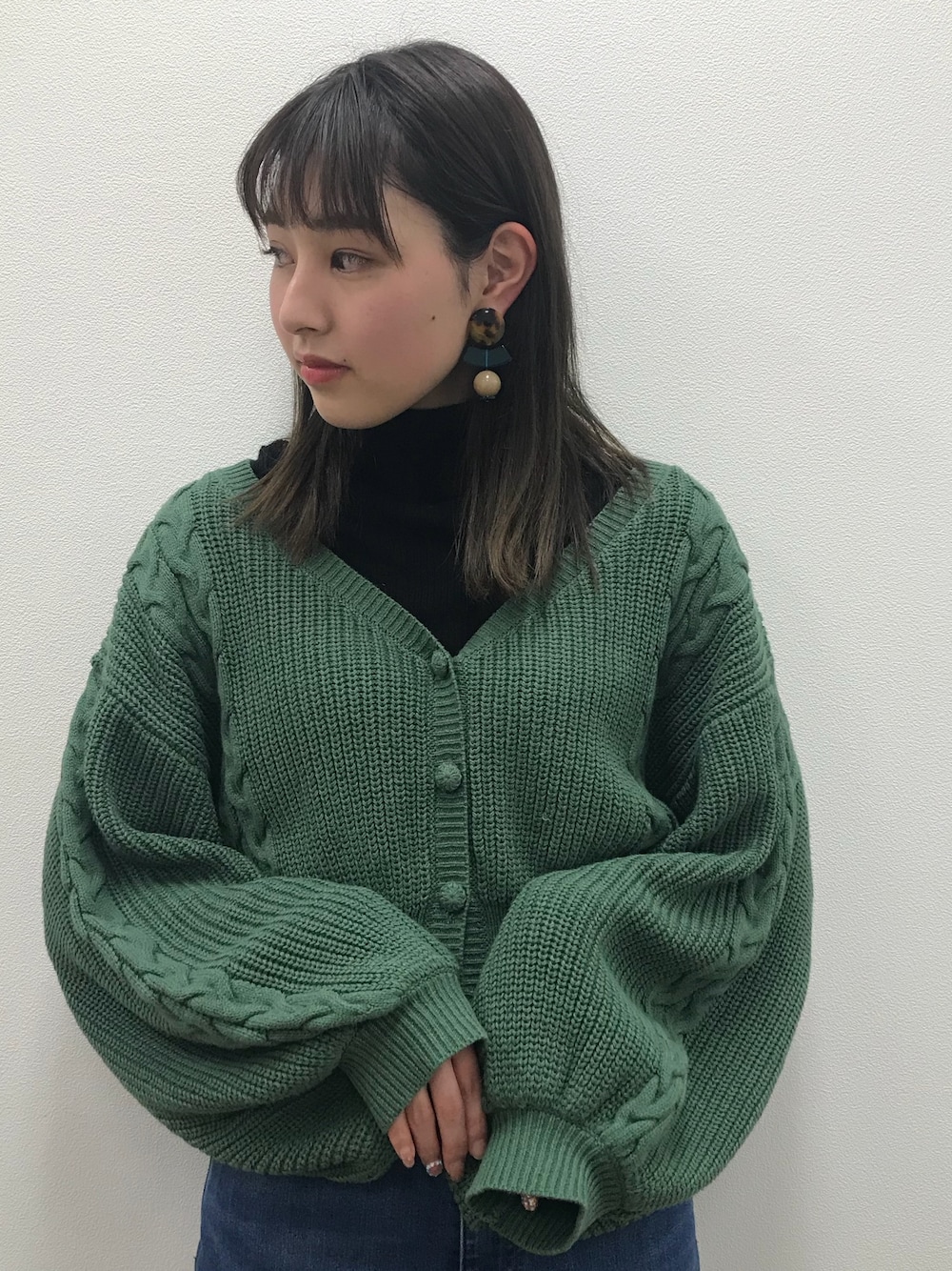 グリーン系のカーディガン/ボレロ、ブラウン系のイヤリングを着用したレディースの春コーディネートの1枚目の写真