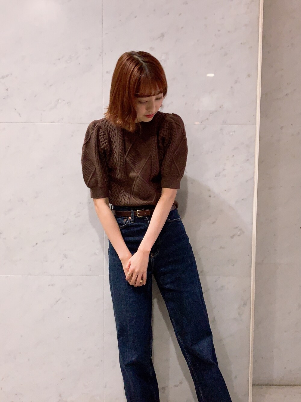 ブラウン系のニット/セーター、ブルー系のデニムパンツを着用したレディースの秋コーディネートの1枚目の写真