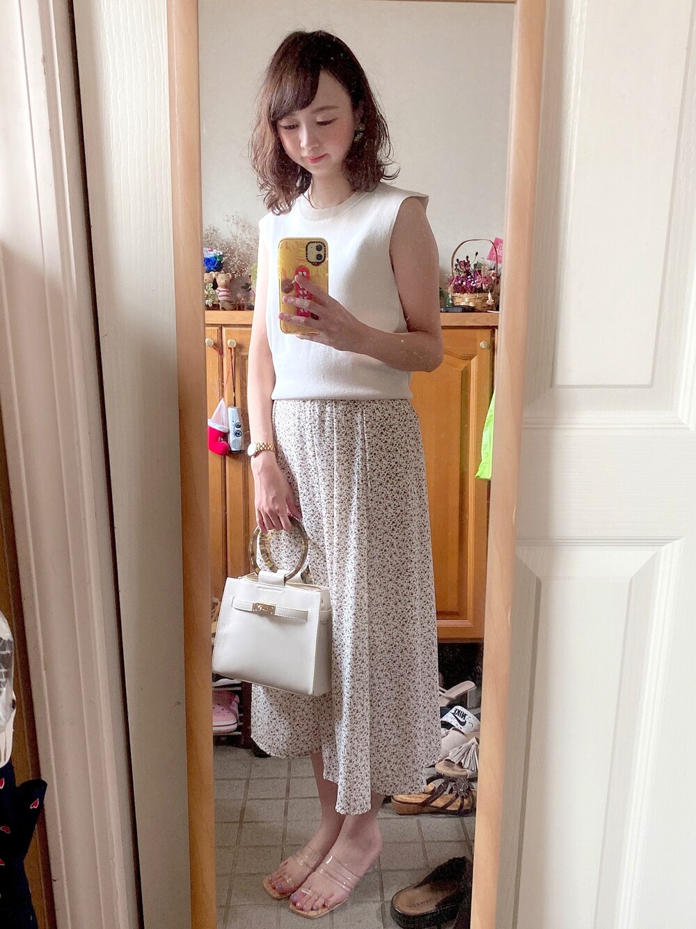 ホワイト系のニット/セーター、ホワイト系のスカート、ホワイト系のショルダーバッグを着用したレディースの夏コーディネートの1枚目の写真
