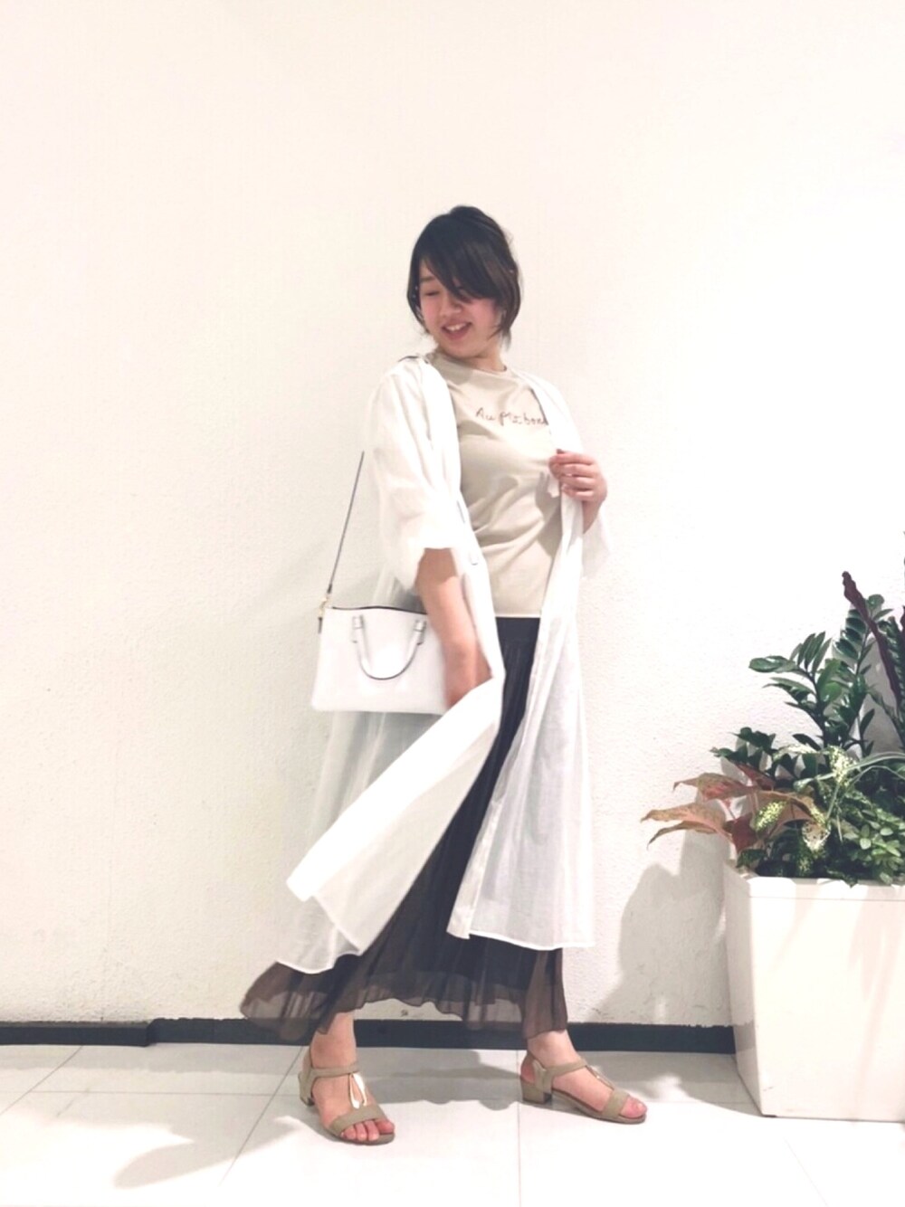 ベージュ系のTシャツ/カットソー、ブラウン系のスカート、ホワイト系のワンピース/ドレスを着用したレディースの春コーディネートの1枚目の写真