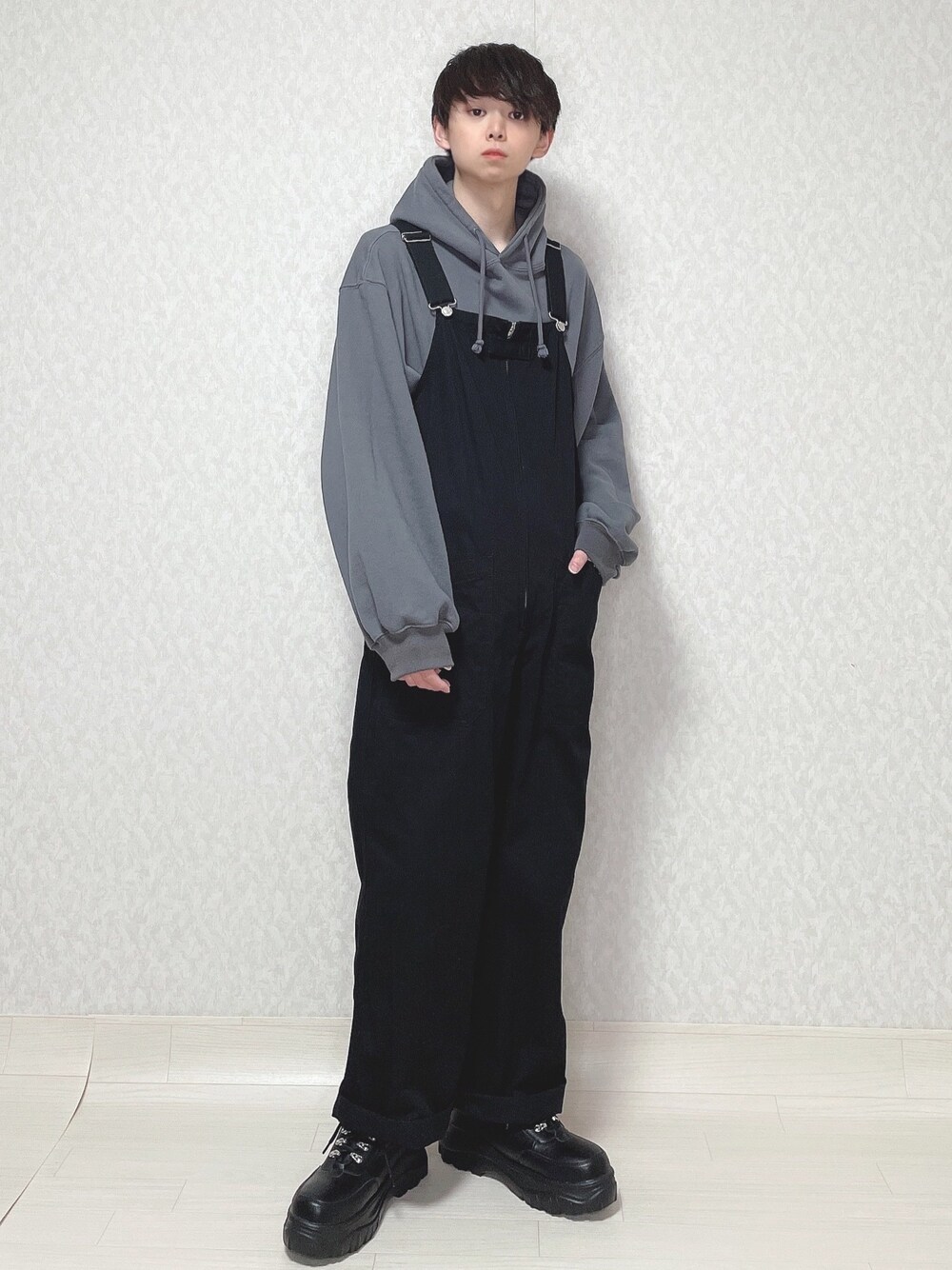 ブルー系のTシャツ/カットソー、ブラック系のサロペット/オーバーオール、ブラック系のスニーカーを着用したメンズの冬コーディネートの1枚目の写真