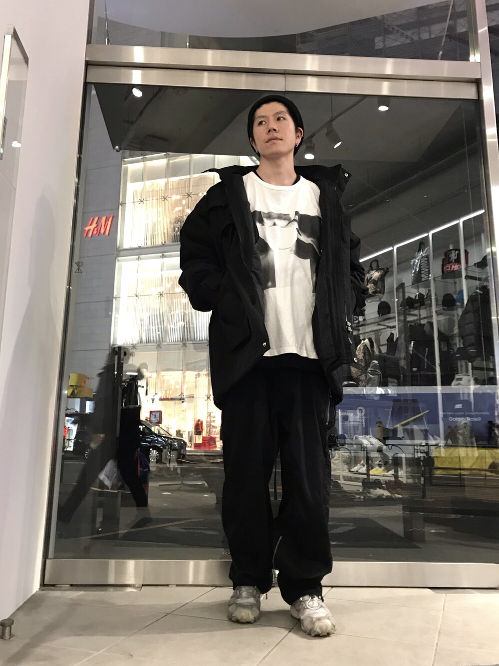 ブラック系のパンツ、シルバー系のスニーカー、ブラック系のミリタリージャケットを着用したメンズの秋コーディネートの1枚目の写真