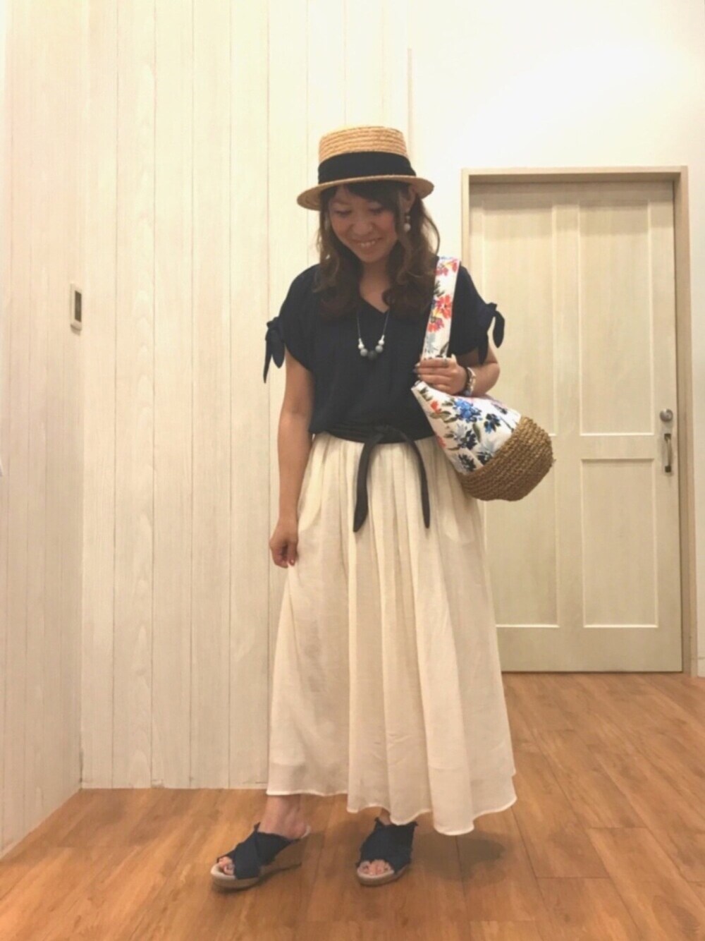 ホワイト系のトートバッグ、ホワイト系のスカート、ブルー系のサンダルを着用したレディースの夏コーディネートの1枚目の写真