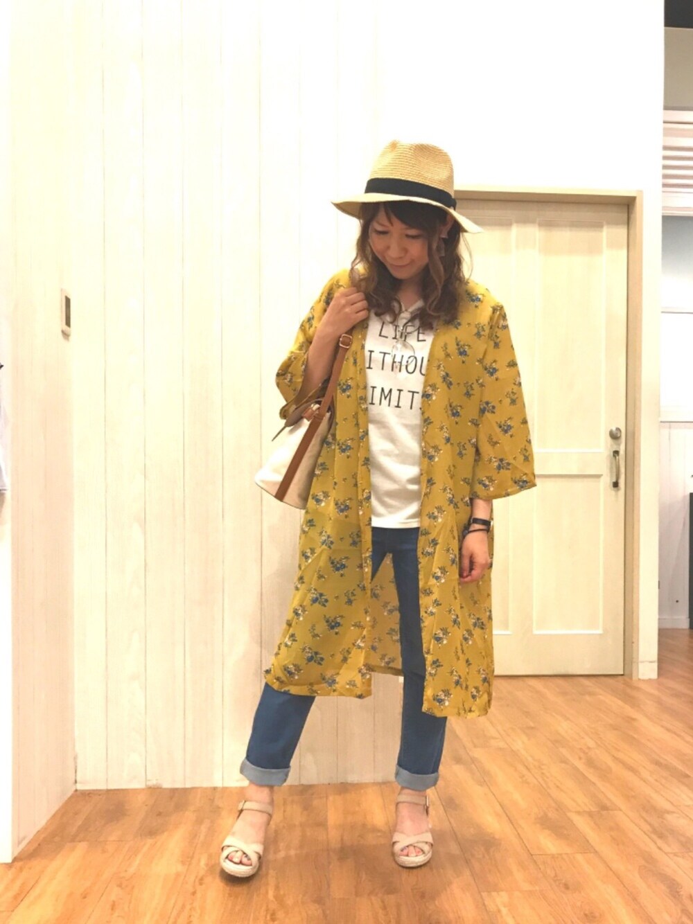 イエロー系のシャツワンピース、ブラウン系のショルダーバッグ、ブルー系のデニムパンツを着用したレディースの夏コーディネートの1枚目の写真