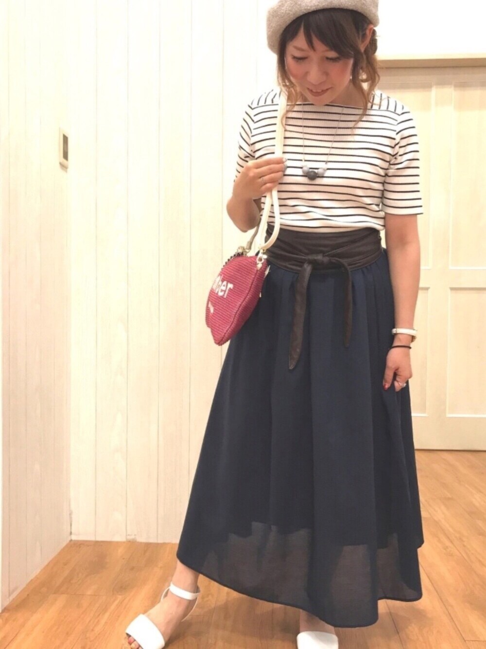 ピンク系のクラッチバッグ、ブルー系のスカート、ホワイト系のサンダルを着用したレディースの夏コーディネートの1枚目の写真