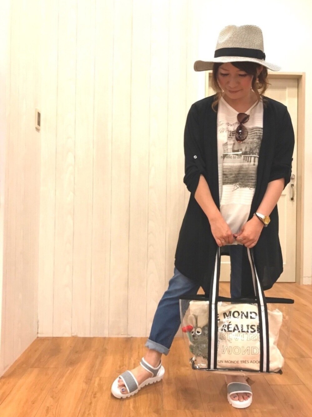 ブラック系のカーディガン/ボレロ、ブルー系のデニムパンツ、ブラック系のトートバッグを着用したレディースの夏コーディネートの1枚目の写真