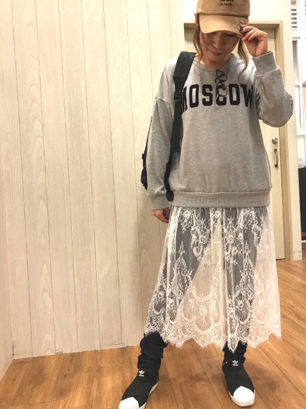 グレー系のワンピース、ブラック系のバックパック/リュック、ブルー系のデニムパンツを着用したレディースの秋コーディネートの1枚目の写真