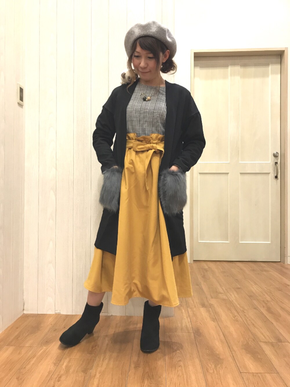 ホワイト系のTシャツ/カットソー、ブラック系のカーディガン/ボレロ、イエロー系のスカートを着用したレディースの秋コーディネートの1枚目の写真