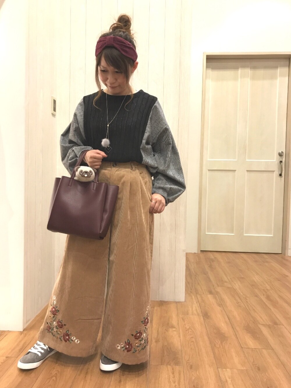 ブラック系のトップス、ベージュ系のパンツ、レッド系のトートバッグを着用したレディースの秋コーディネートの1枚目の写真