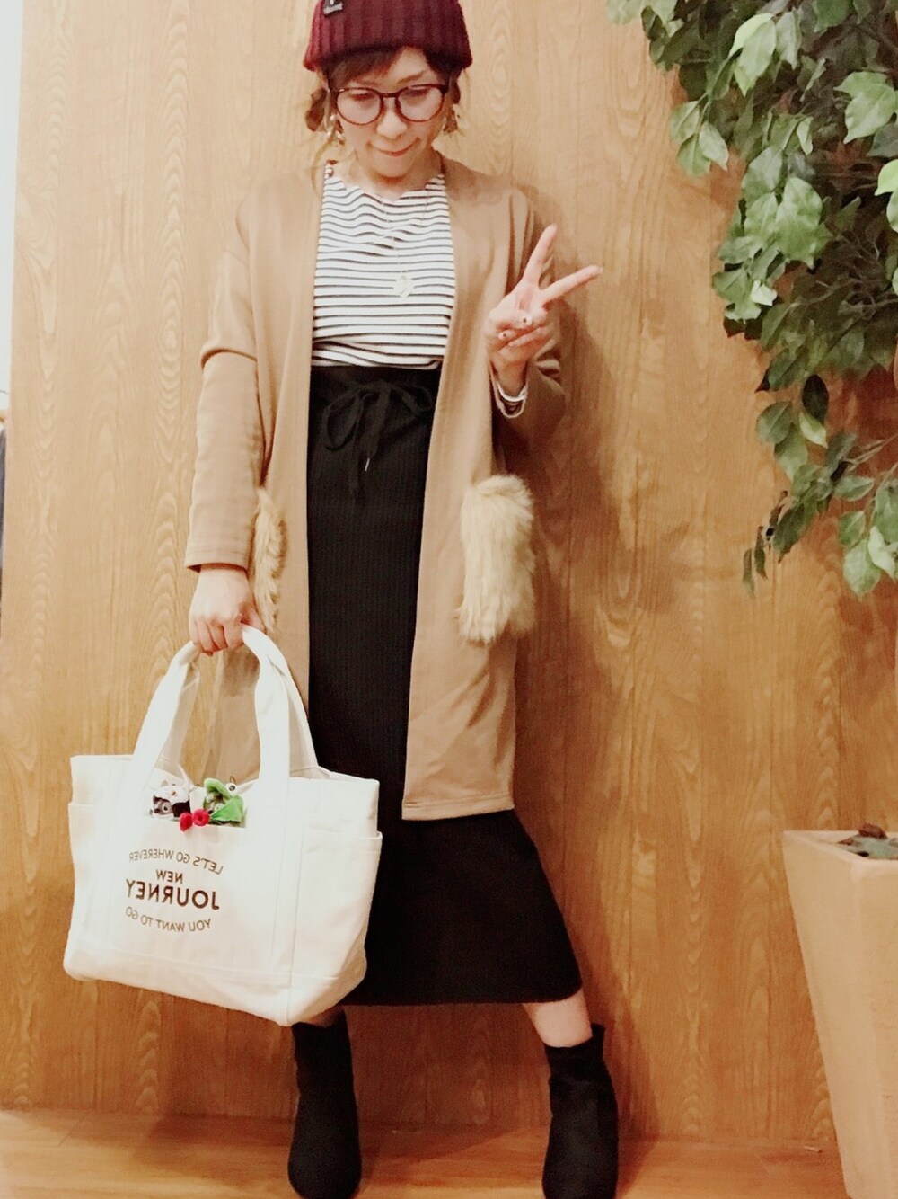 ブラック系のトップス、ベージュ系のカーディガン/ボレロ、ブラック系のスカートを着用したレディースの秋コーディネートの1枚目の写真