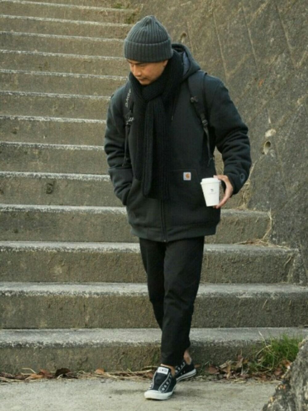 ブラック系のスリッポン、ブラック系のバックパック/リュック、ブラック系のチノパンツを着用したメンズの冬コーディネートの1枚目の写真