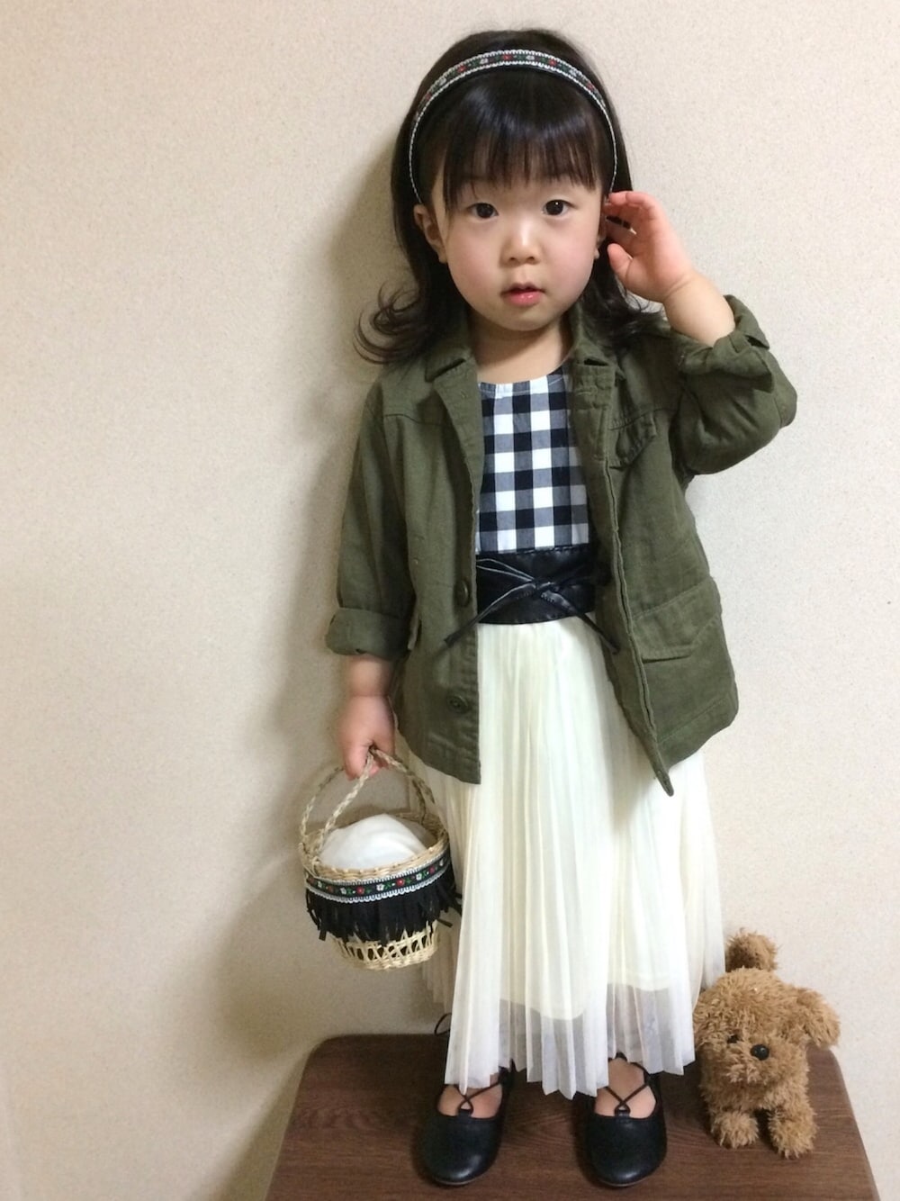 グリーン系のミリタリージャケット、ホワイト系のスカート、ブラック系のバレエシューズを着用したキッズの春コーディネートの1枚目の写真