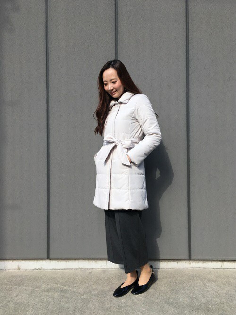 グレー系のステンカラーコート、ブラック系のその他パンツを着用したレディースの冬コーディネートの1枚目の写真