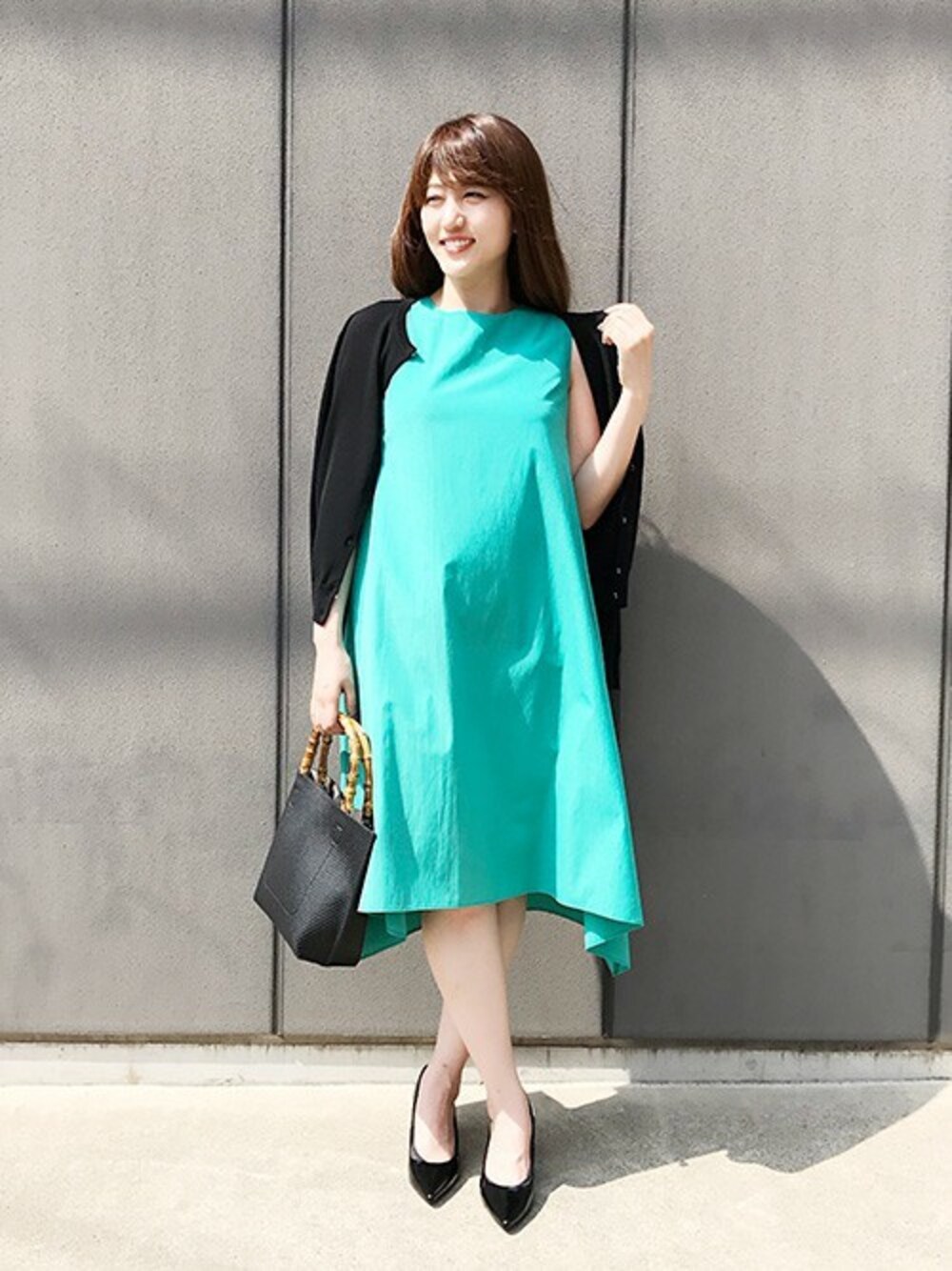 グリーン系のワンピース、ブラック系のカーディガン/ボレロ、ブラック系のトートバッグを着用したレディースの夏コーディネートの1枚目の写真