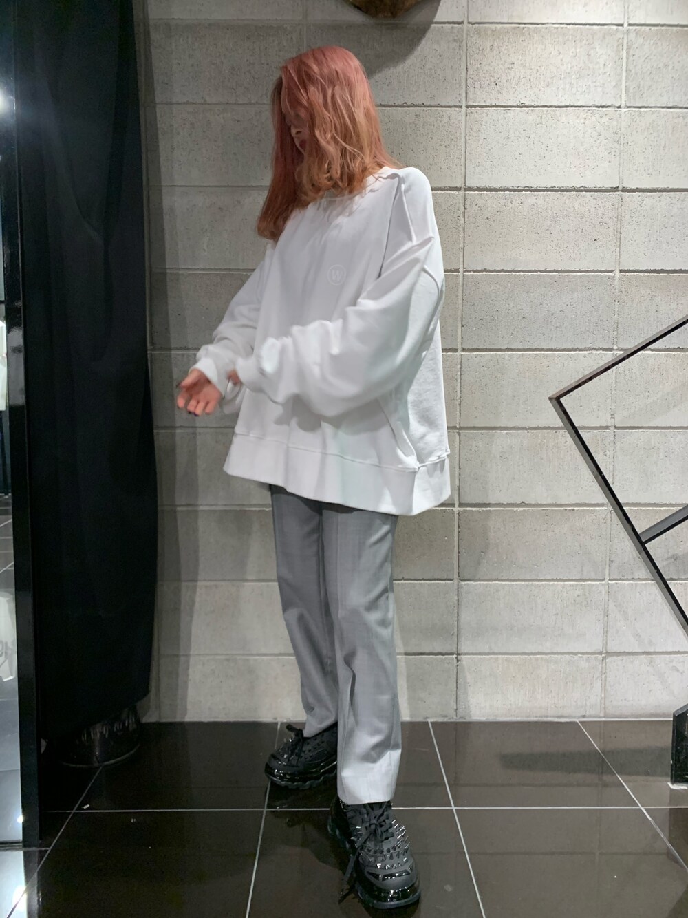 ホワイト系のスウェット、グレー系のスラックス、ブラック系のスニーカーを着用したレディースの春コーディネートの1枚目の写真