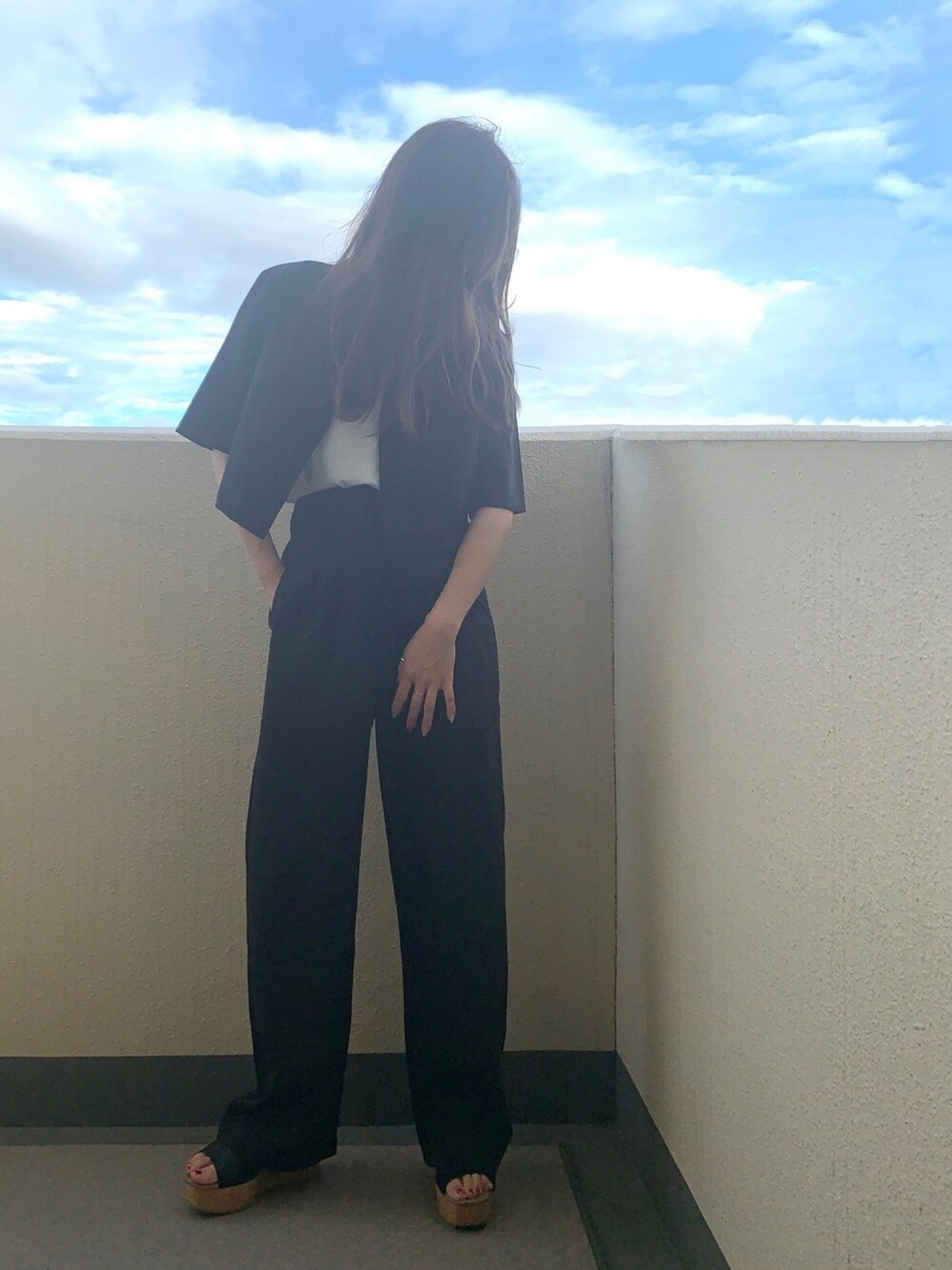 ブラック系のセットアップ、ホワイト系のTシャツ/カットソー、ブラック系のサンダルを着用したレディースの秋コーディネートの1枚目の写真