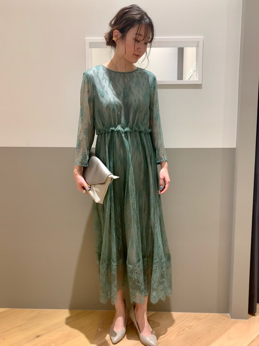 グリーン系のドレス、ベージュ系のトートバッグ、シルバー系のパンプスを着用したレディースの冬コーディネートの1枚目の写真