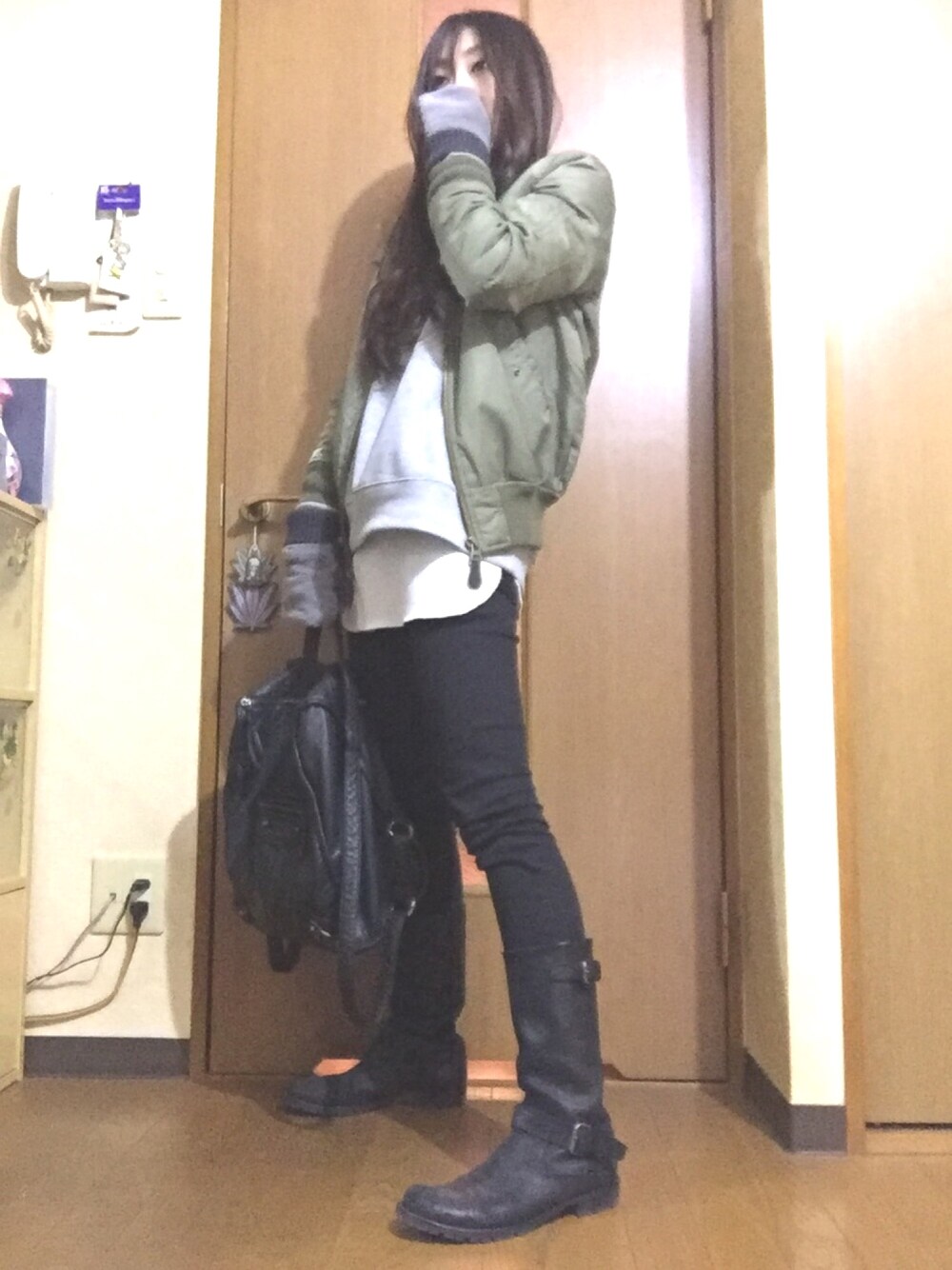 グリーン系のブルゾン、ホワイト系のタンクトップ、ブラック系のデニムパンツを着用したレディースの冬コーディネートの1枚目の写真