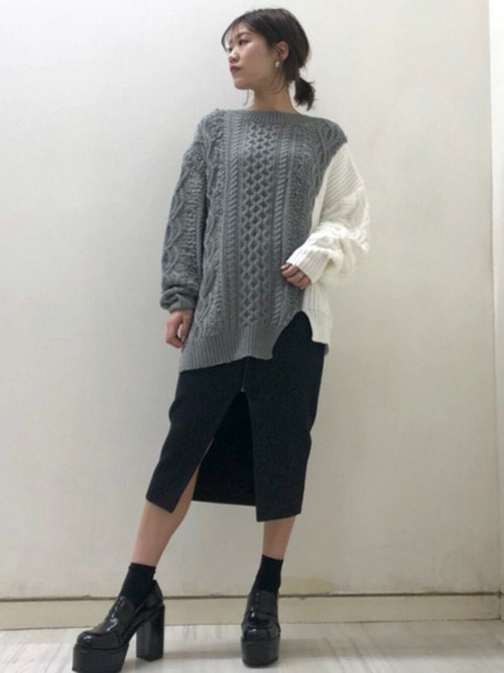 グレー系のニット/セーター、ブラック系のスカート、ブラック系のローファーを着用したレディースの冬コーディネートの1枚目の写真