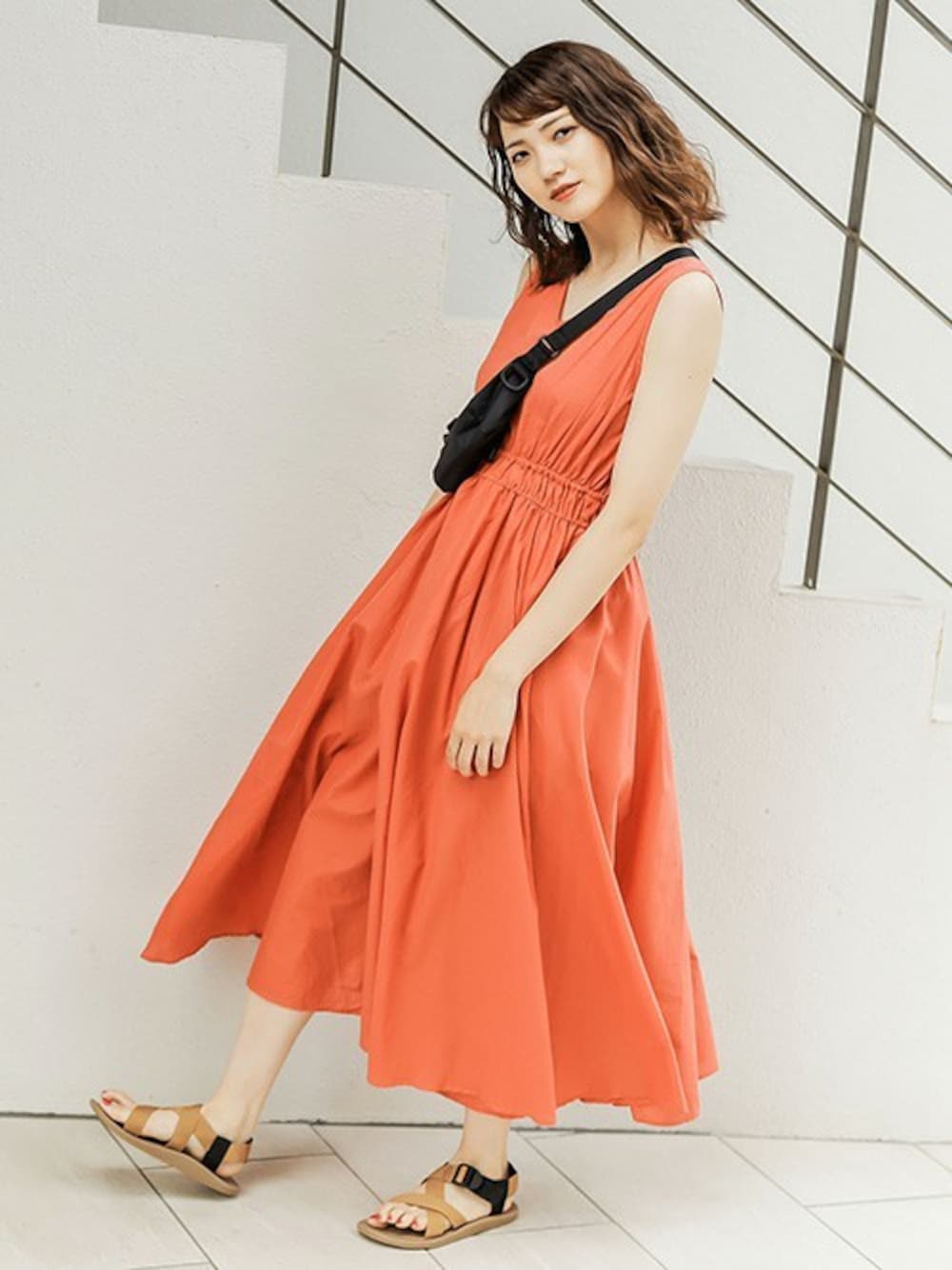 オレンジ系のワンピース、ブラック系のボディバッグ/ウエストポーチ、ベージュ系のサンダルを着用したレディースの夏コーディネートの1枚目の写真