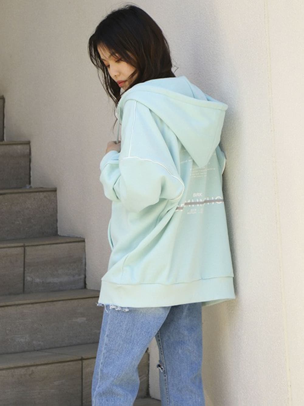 グリーン系のパーカー、ブルー系のデニムパンツを着用したレディースの春コーディネートの1枚目の写真