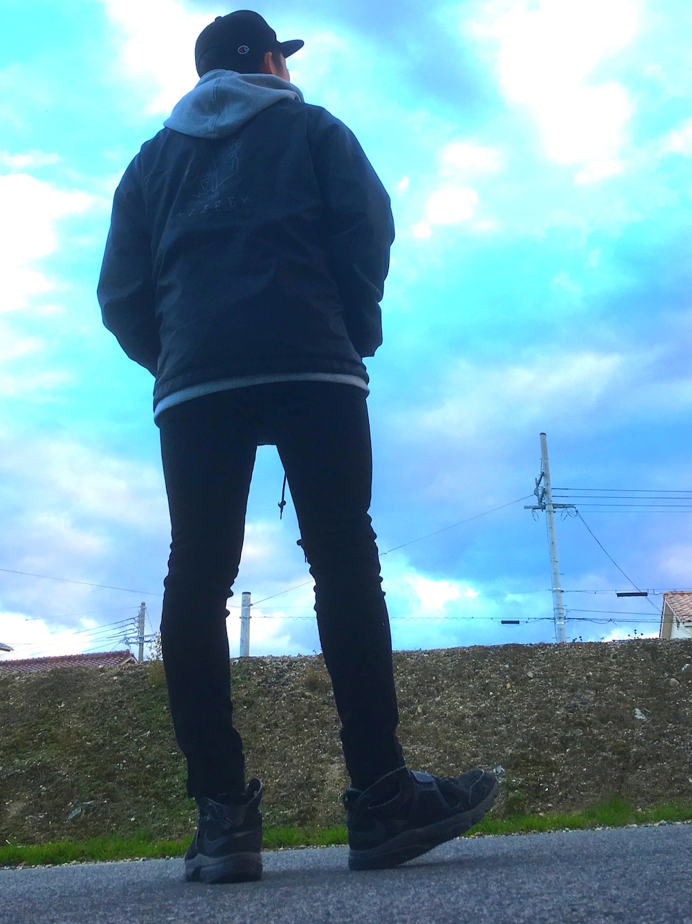 グレー系のパーカー、ブラック系のナイロンジャケット、ブラック系のデニムパンツを着用したメンズの冬コーディネートの1枚目の写真