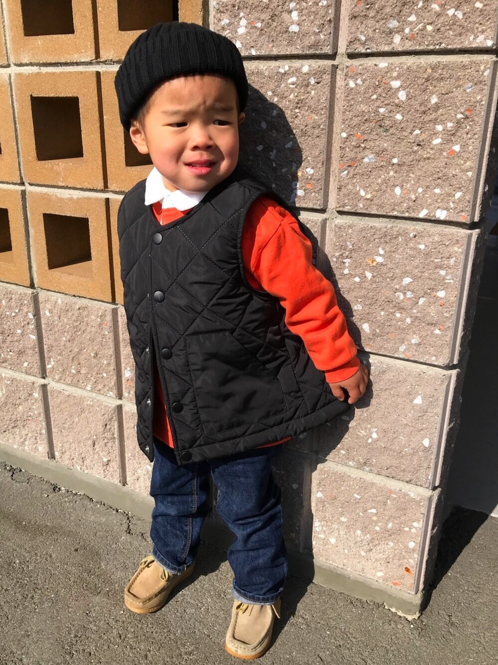 ベージュ系のモカシン/デッキシューズ、ブルー系のデニムパンツ、ブラック系のベストを着用したキッズの冬コーディネートの1枚目の写真