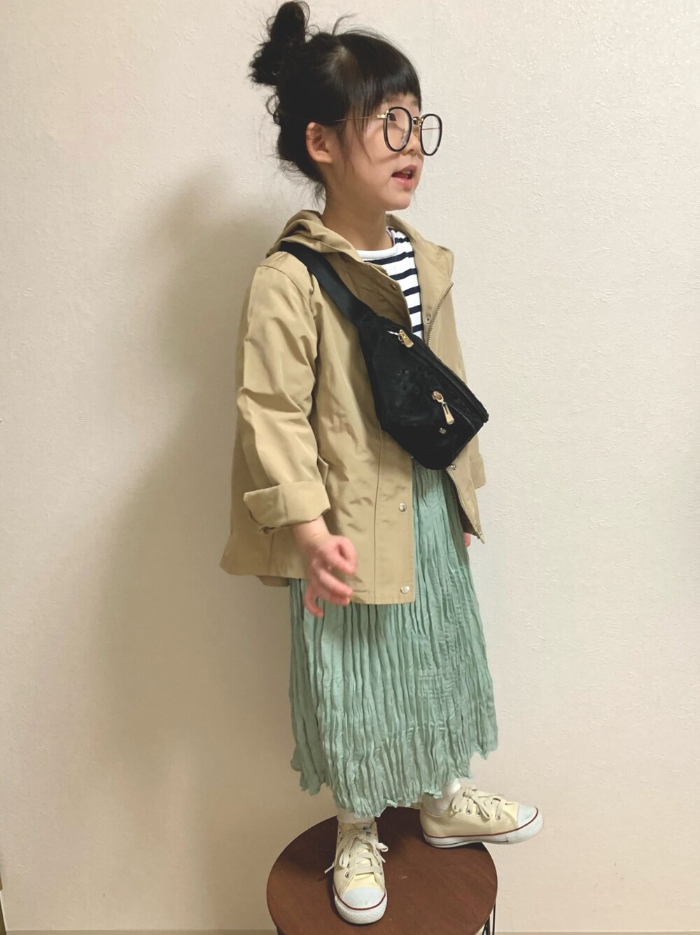 ベージュ系のマウンテンパーカー、グリーン系のスカート、ホワイト系のスニーカーを着用したキッズの春コーディネートの1枚目の写真