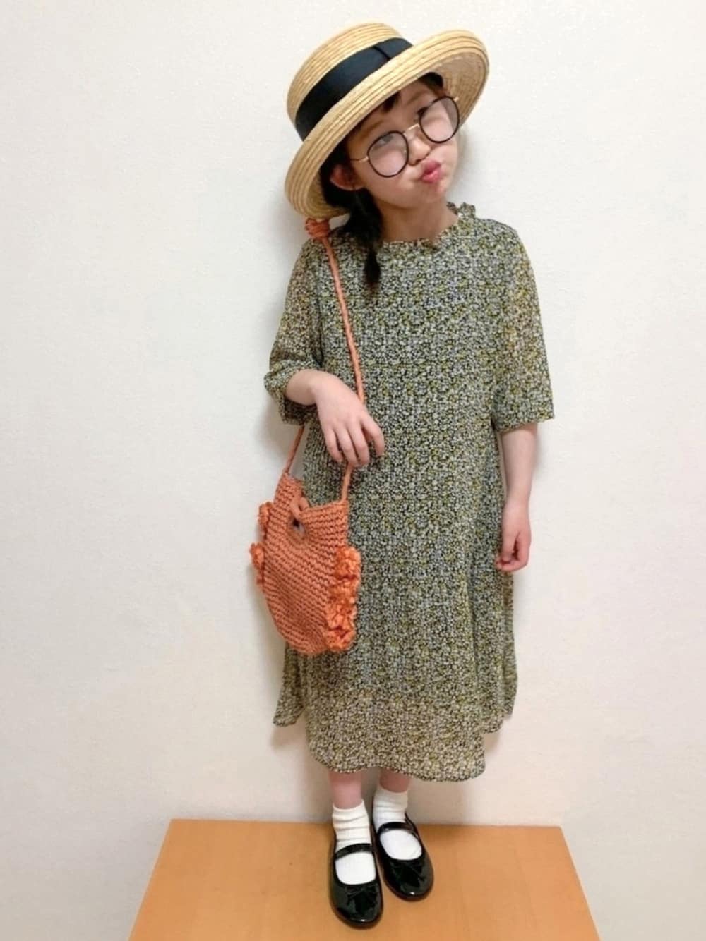 イエロー系のワンピース、オレンジ系のバッグ、ブラック系のバレエシューズを着用したキッズの春コーディネートの1枚目の写真