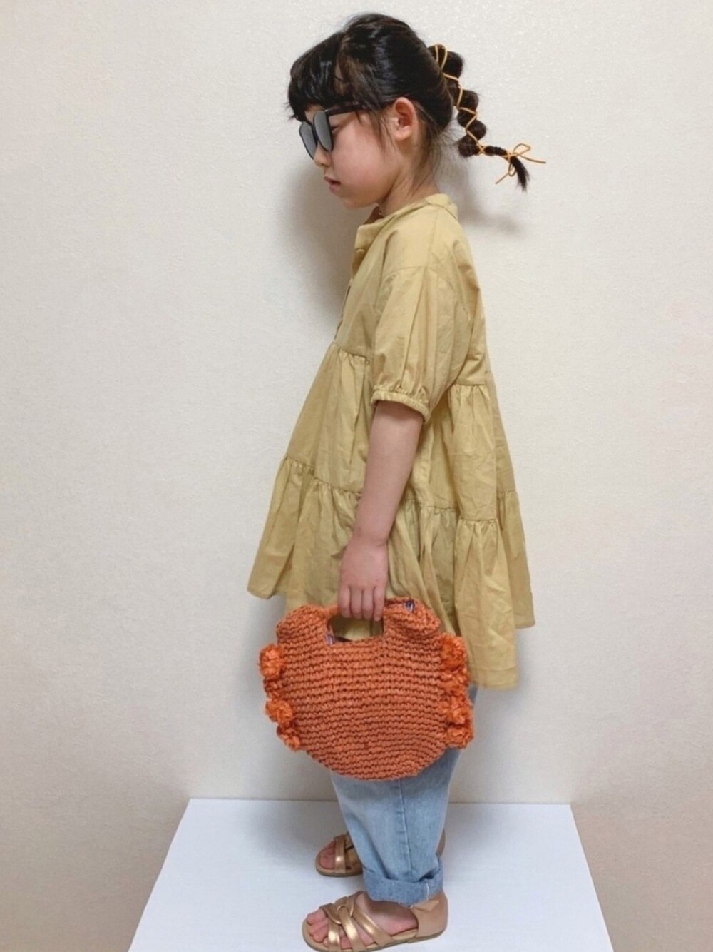 オレンジ系のシャツ/ブラウス、ブルー系のデニムパンツ、オレンジ系のバッグを着用したキッズの春コーディネートの1枚目の写真
