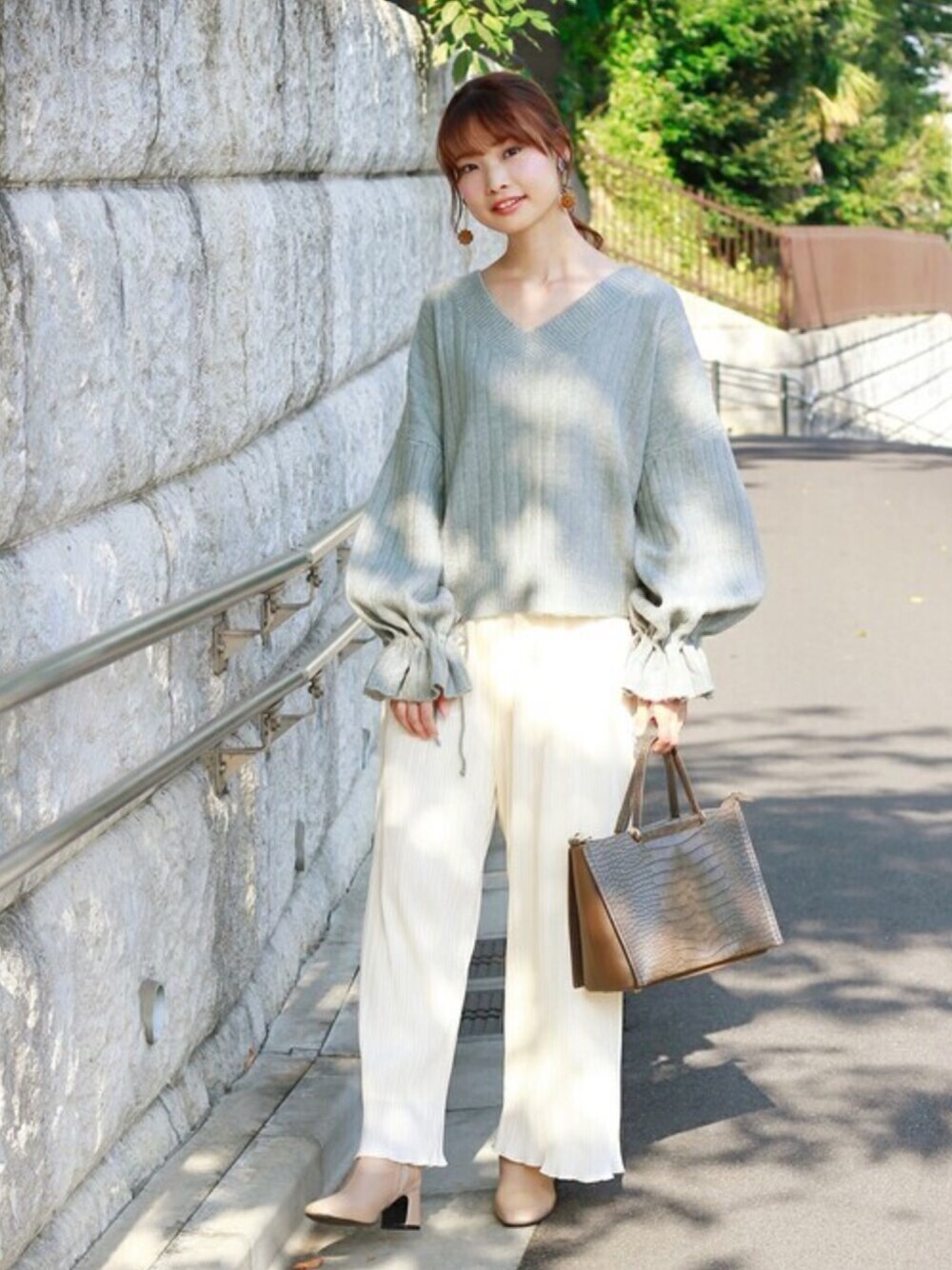 ブルー系のニット/セーター、ベージュ系のその他パンツ、ブラウン系のハンドバッグを着用したレディースの秋コーディネートの1枚目の写真