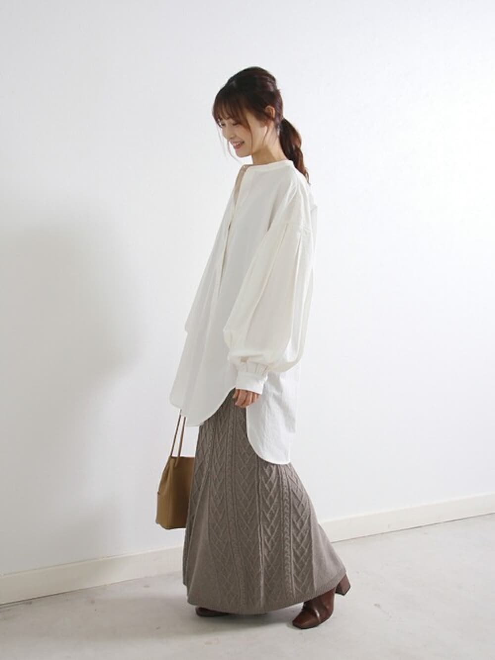 ホワイト系のシャツ/ブラウス、グレー系のスカート、ベージュ系のショルダーバッグを着用したレディースの冬コーディネートの1枚目の写真