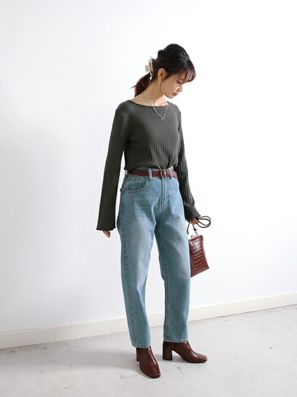 グレー系のTシャツ/カットソー、ブルー系のデニムパンツ、ブラウン系のショルダーバッグを着用したレディースの冬コーディネートの1枚目の写真