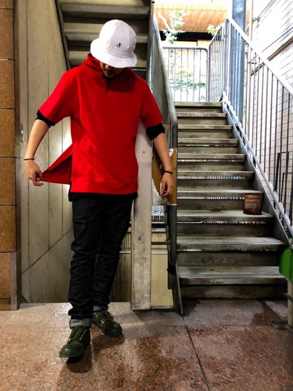 レッド系のトップス、ブルー系のデニムパンツ、グリーン系のスニーカーを着用したメンズの春コーディネートの1枚目の写真