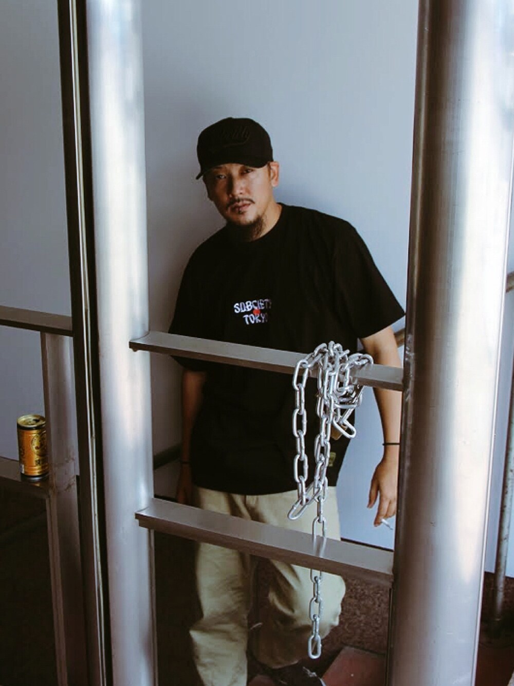 ブラック系のTシャツ/カットソー、ベージュ系のチノパンツ、ブラック系のキャップを着用したメンズの夏コーディネートの1枚目の写真