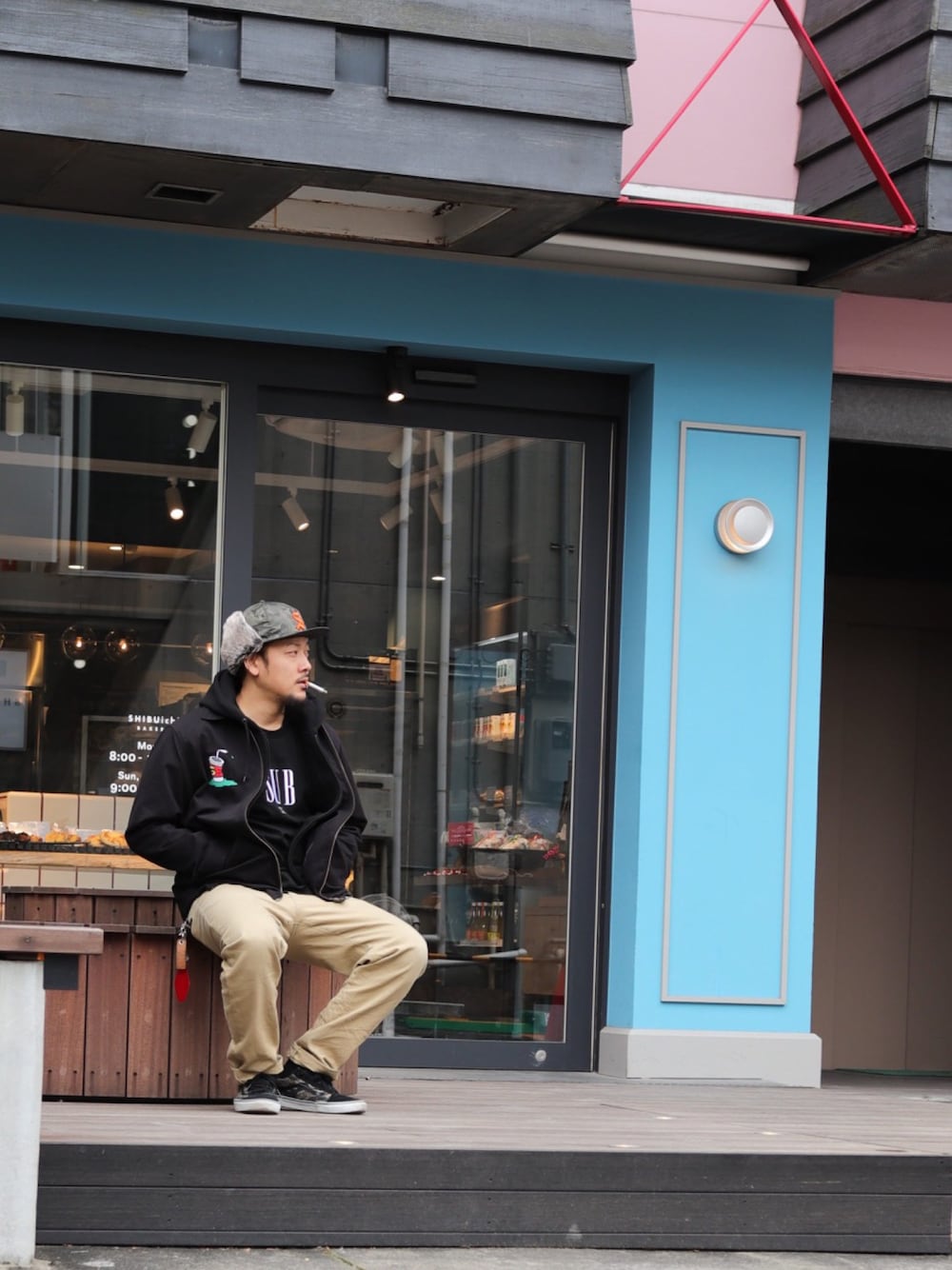 ベージュ系のチノパンツ、ブラック系のTシャツ/カットソー、ブラック系のミリタリージャケットを着用したメンズの冬コーディネートの1枚目の写真