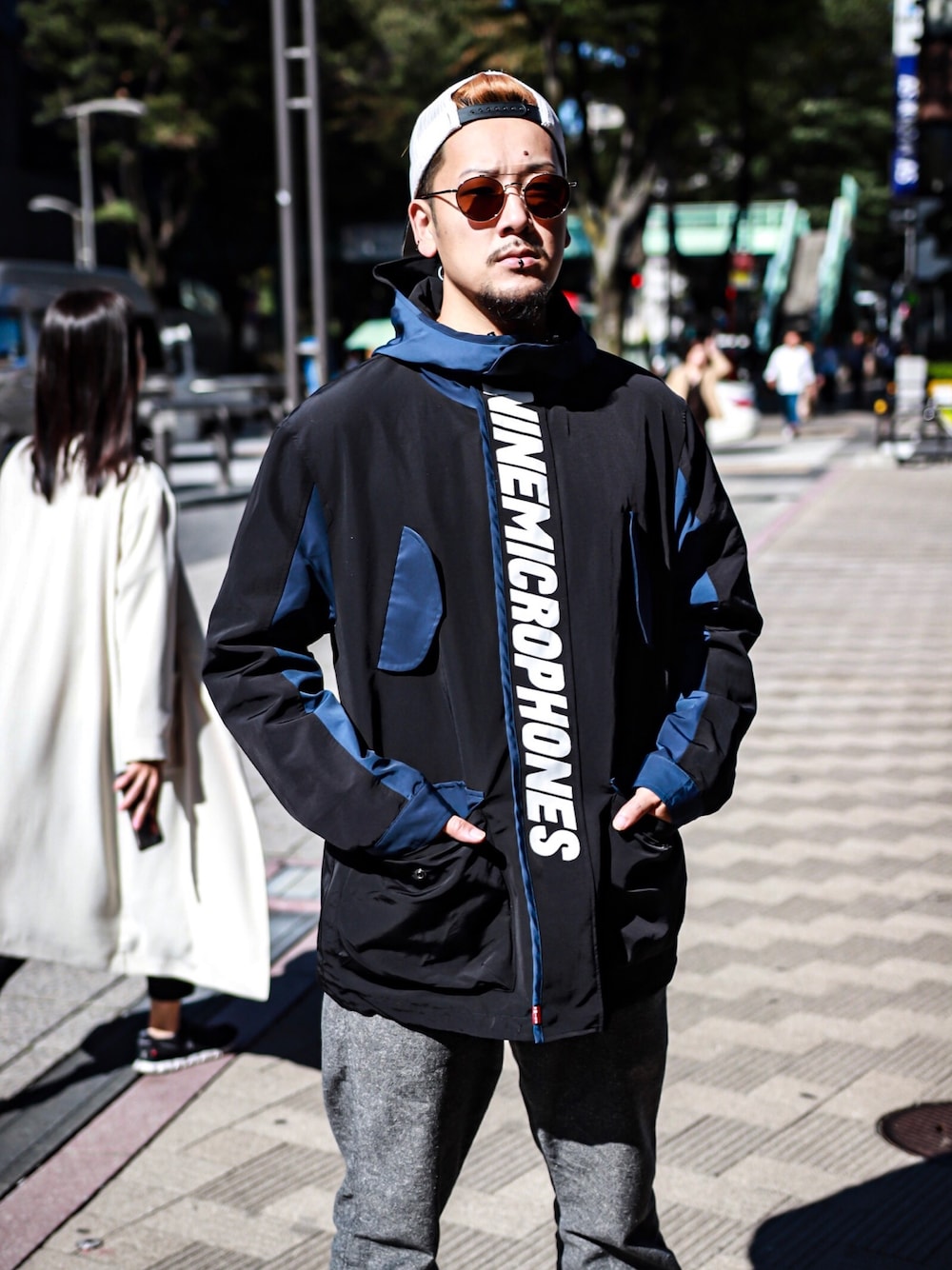 ブラック系のマウンテンパーカー、ブラウン系のサングラス、ホワイト系のキャップを着用したメンズの秋コーディネートの1枚目の写真