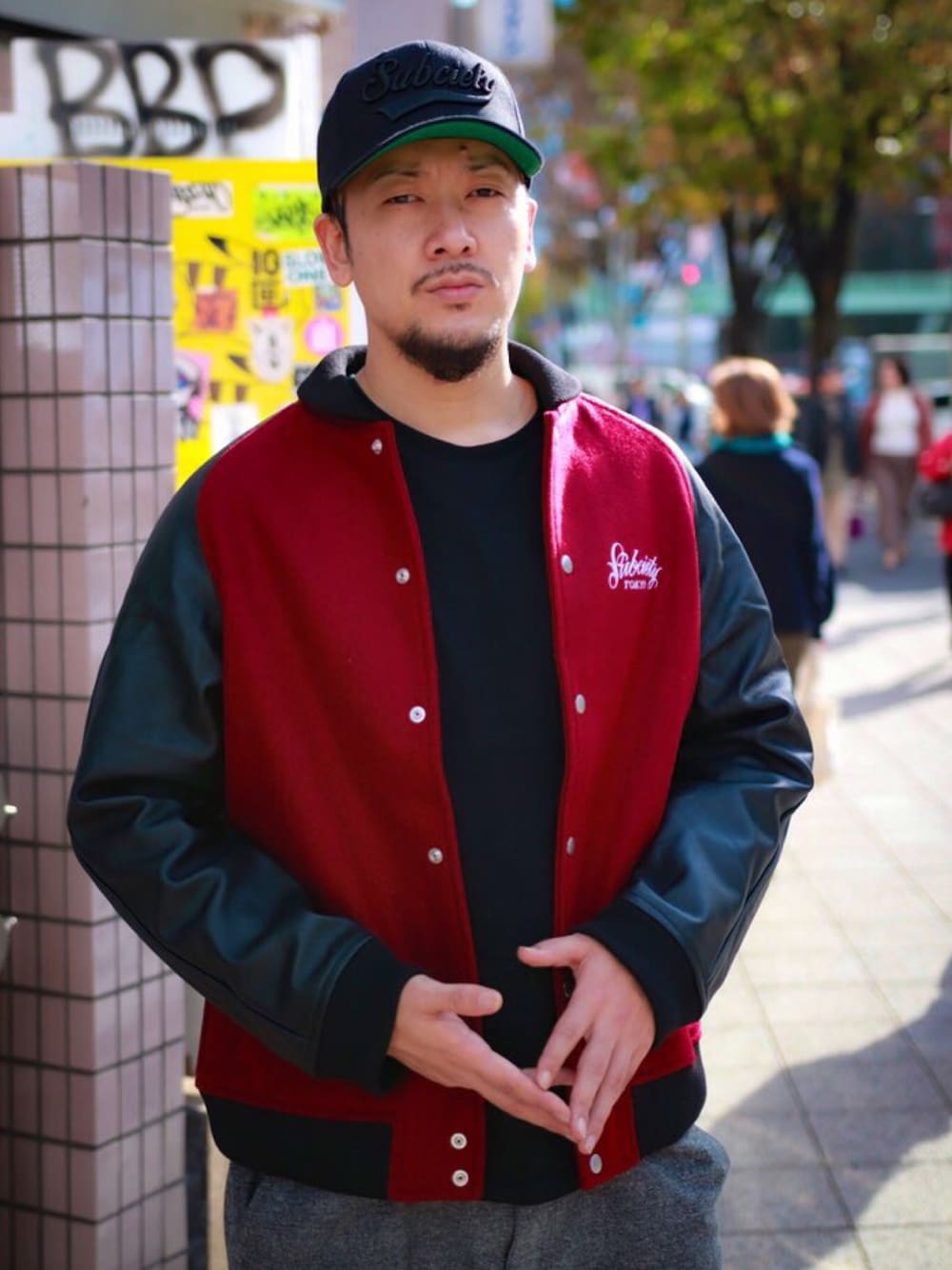 レッド系のスタジャン、ブラック系のキャップを着用したメンズの秋コーディネートの1枚目の写真