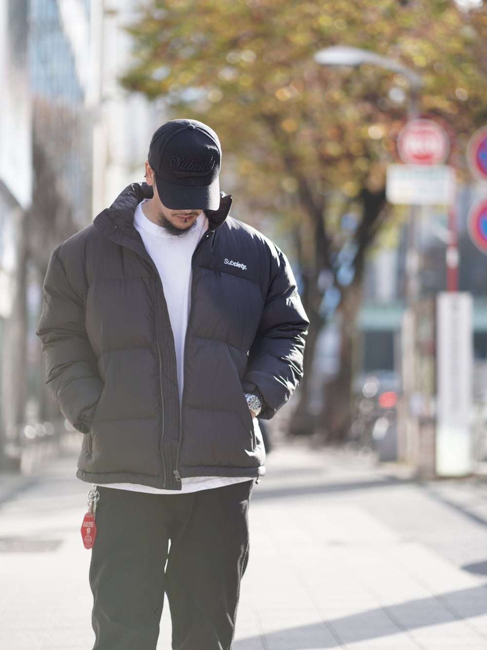 ブラック系のダウンジャケット/コート、ブラック系のキャップ、シルバー系のアナログ腕時計を着用したメンズの冬コーディネートの1枚目の写真